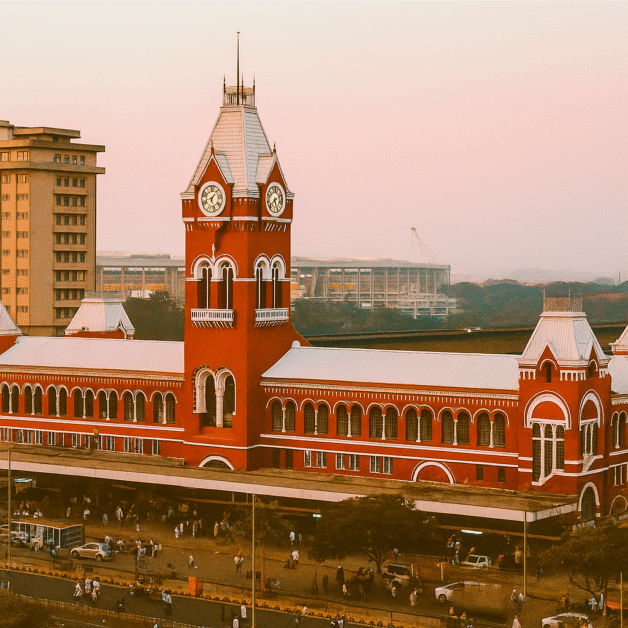 iconic view of the Puratchi Thalaivar Dr. M.G. Ramachandran Central Railway Station, also known as Chennai Central, featuring its distinctive red-brick architecture and clock tower. Chennai Central railway station